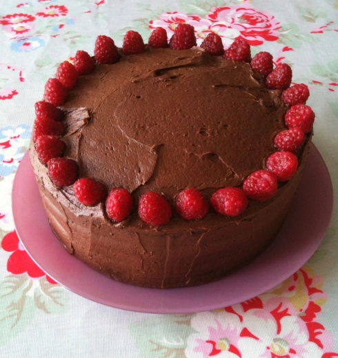 Chocolate cake covered in chocolate buttercream and raspberries