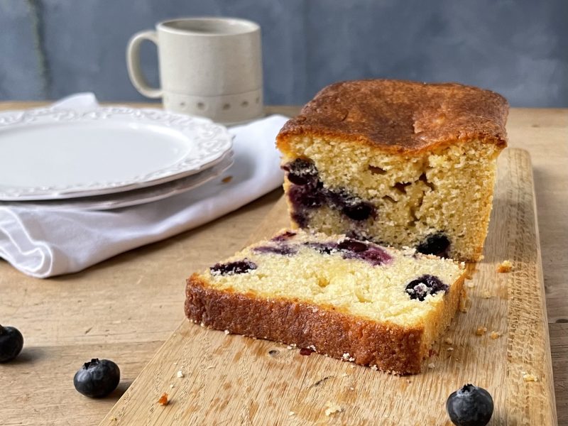 Close-up of a sliced blueberry and lemon loaf cake with a glossy lemon sugar glaze